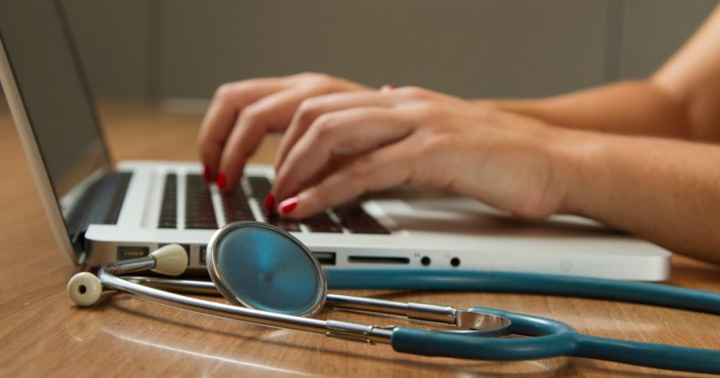Royalty free stock image of a healthcare worker using a laptop found on Unsplash.
