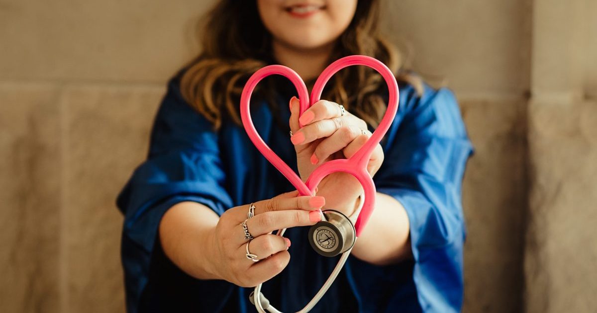 Royalty free stock image of a female healthcare provider holding a stethoscope in the shape of a heart found on Unsplash.